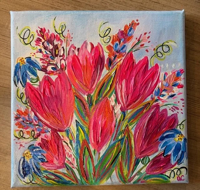 Colorful abstract painting of pink tulips and blue flowers with green leaves on a canvas.