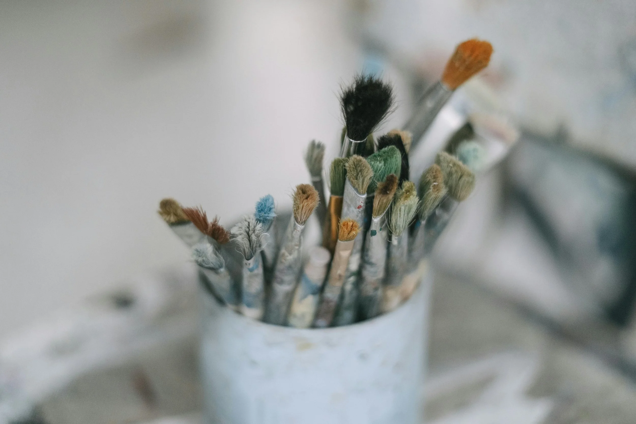 A collection of paintbrushes with various colored bristles arranged in a container.
