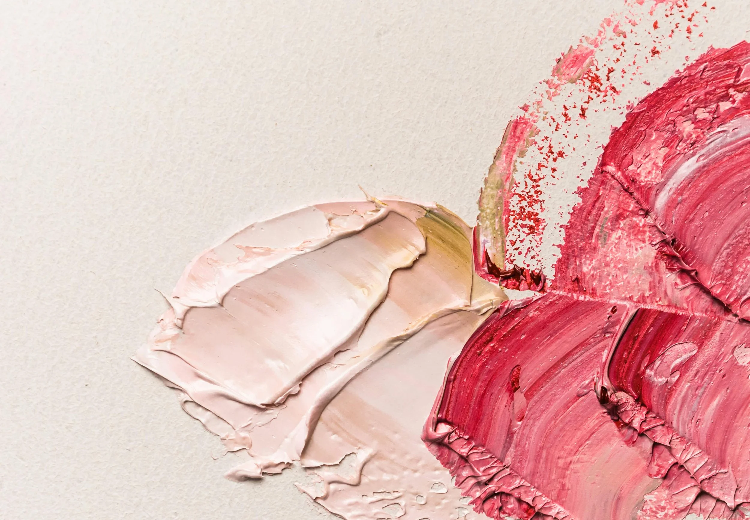 Close-up of pink and red oil paint strokes on a canvas, with thick and textured application.