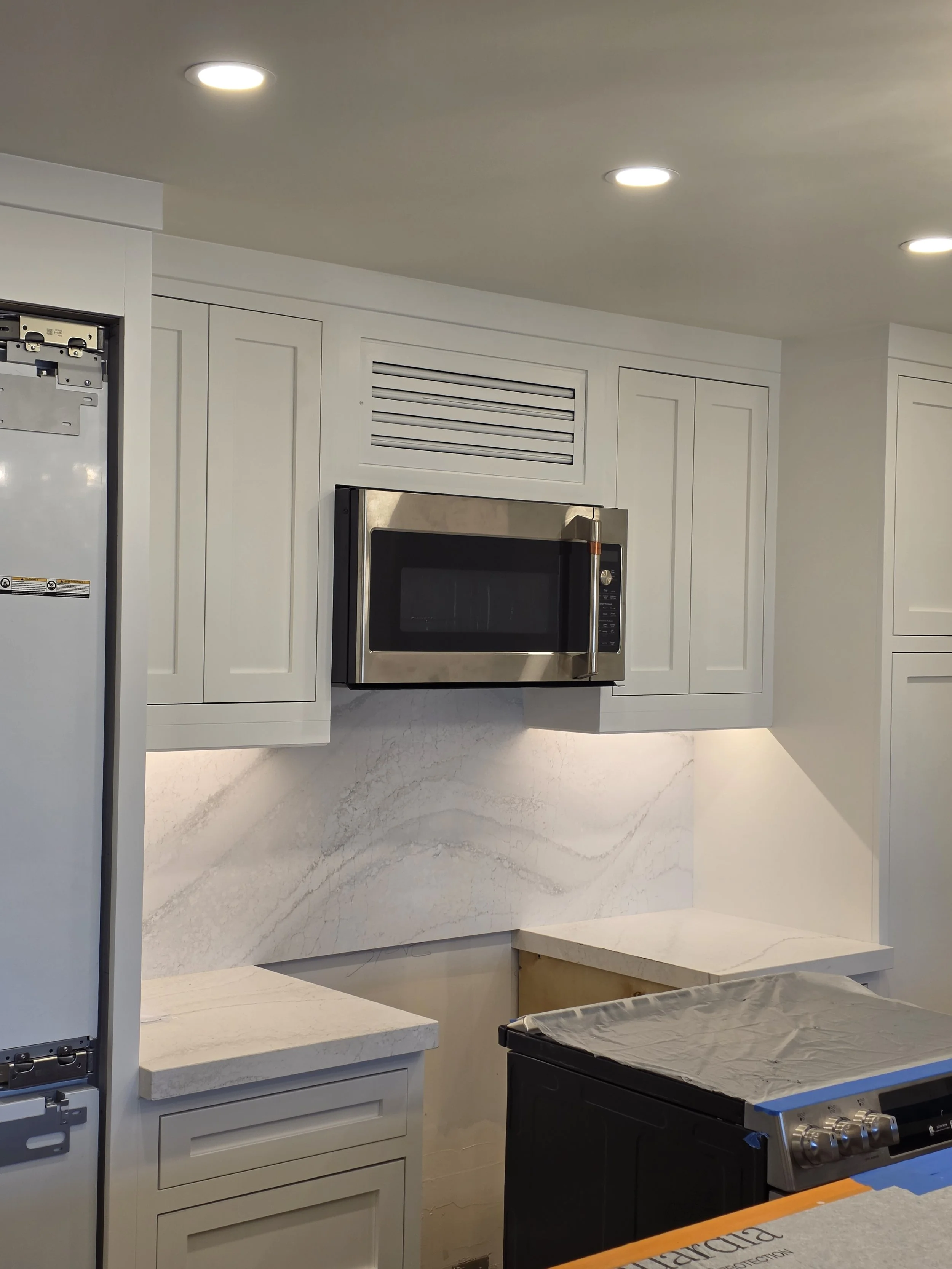 Close up of cabinetry and microwave. Range being installed.