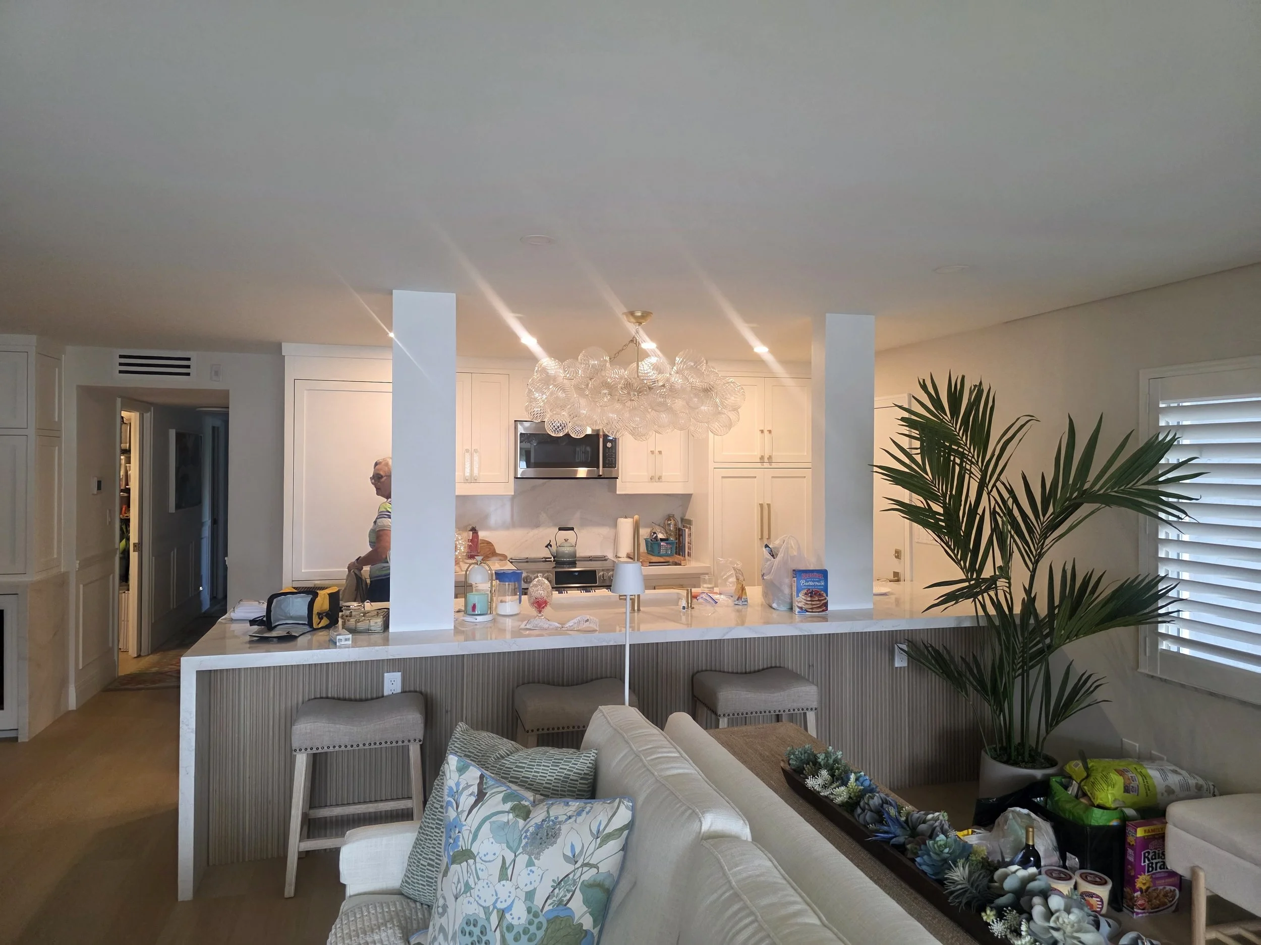 Main kitchen area showing stylish accent lighting with barstools and beautiful waterfall counter tops and custom cabinetry.