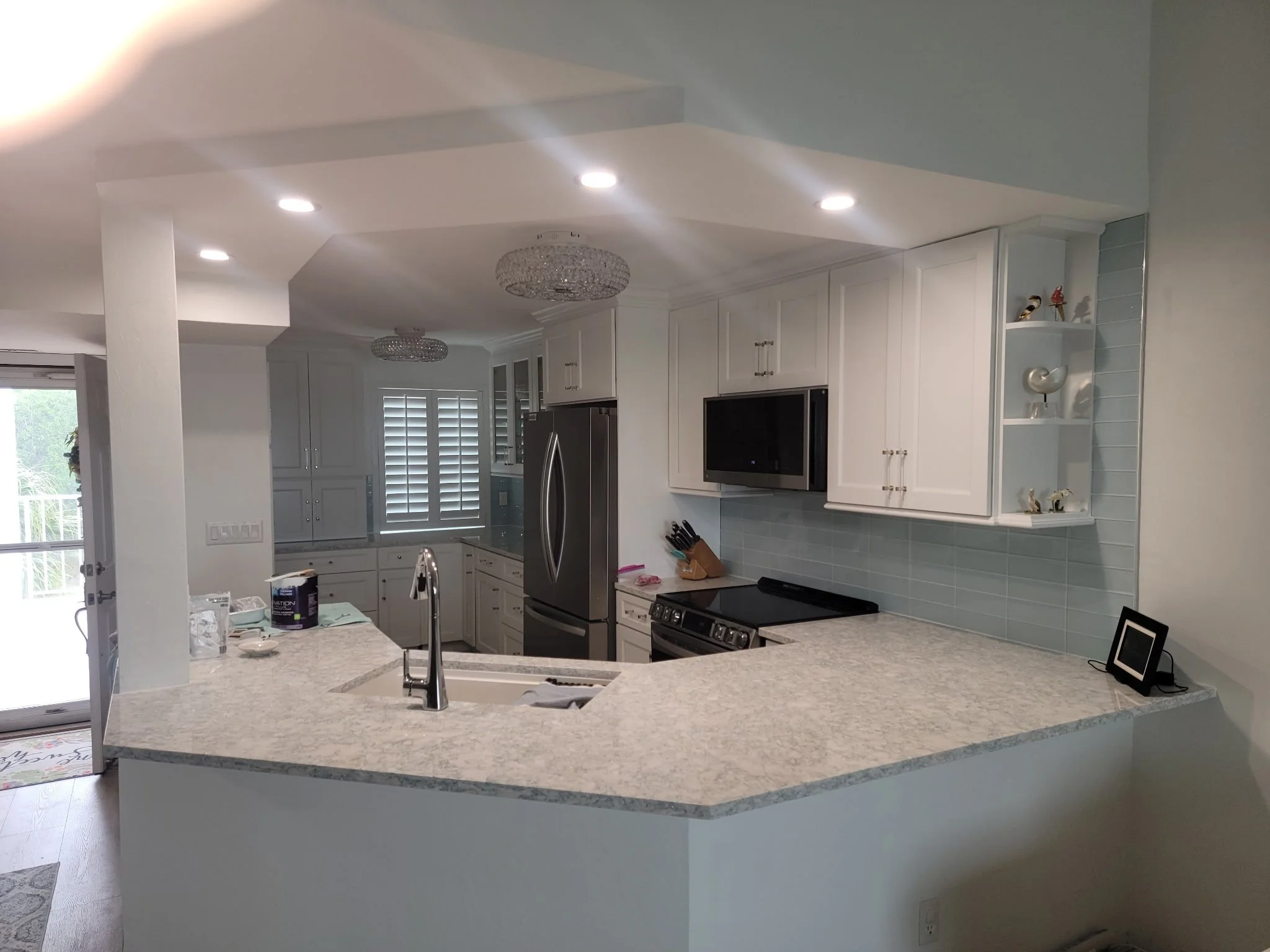 White kitchen cabinets and quartz countertop on horseshoe peninsula.  Dropped ceiling for accent.  Chrome faucet.