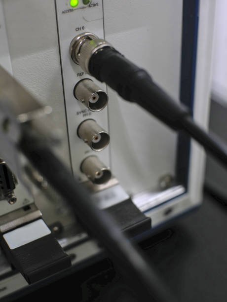 Close-up of the back panel of a piece of electronic equipment with two BNC connectors and a cable plugged into one of them.