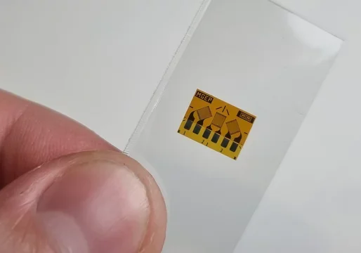 Close-up of a person's thumb holding a small sticker with a caution symbol and the word 'RAGER' printed on it.
