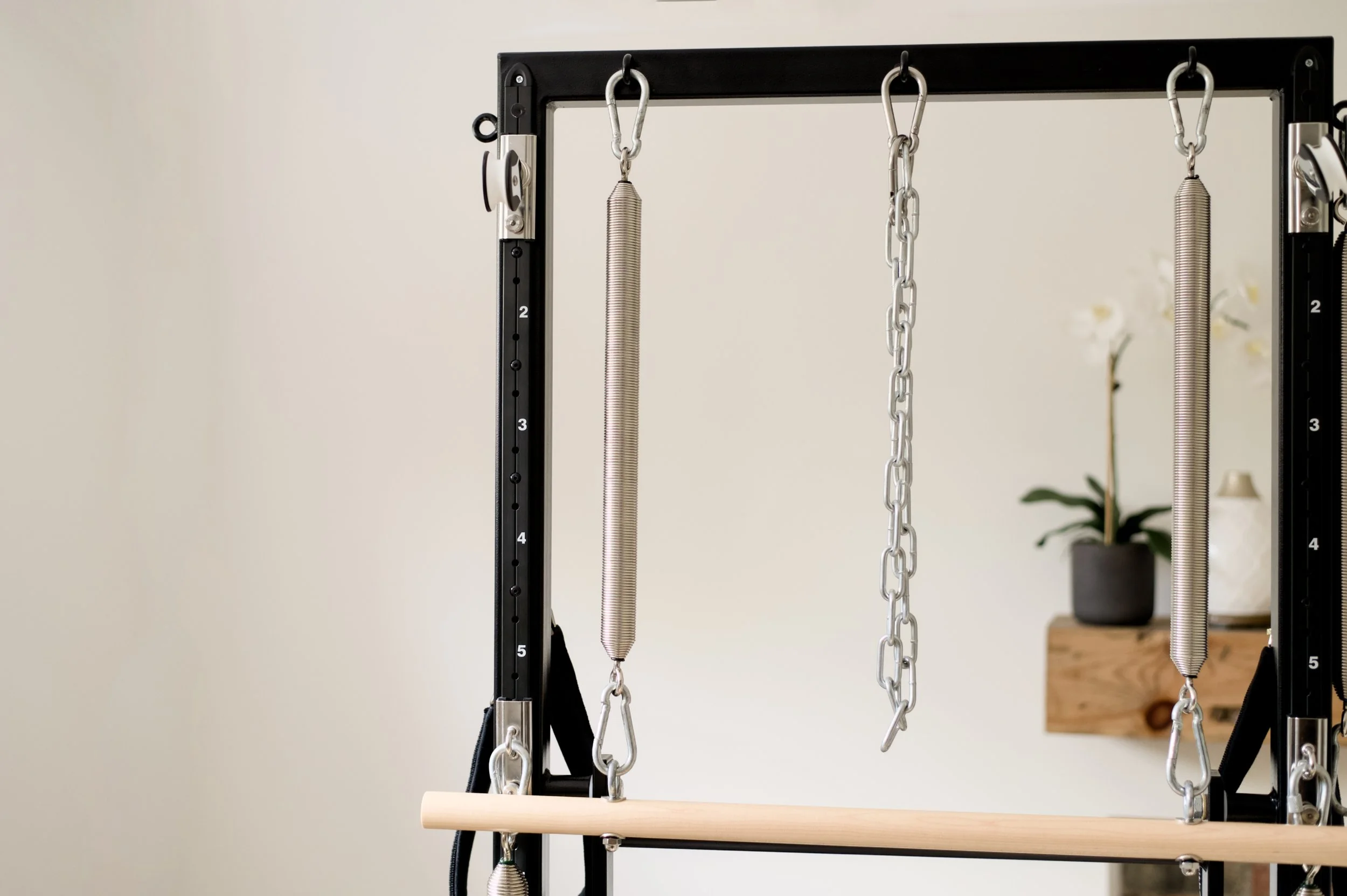 Reformer Pilates machine with springs and chains in a gym or studio setting.