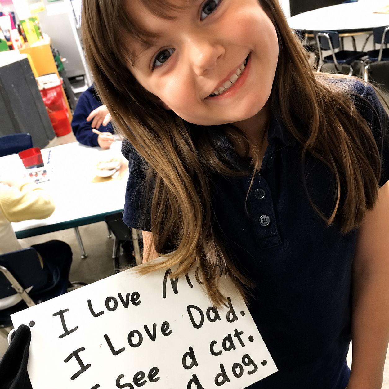 girl showing the kindergarten sight words, heart words she wrote