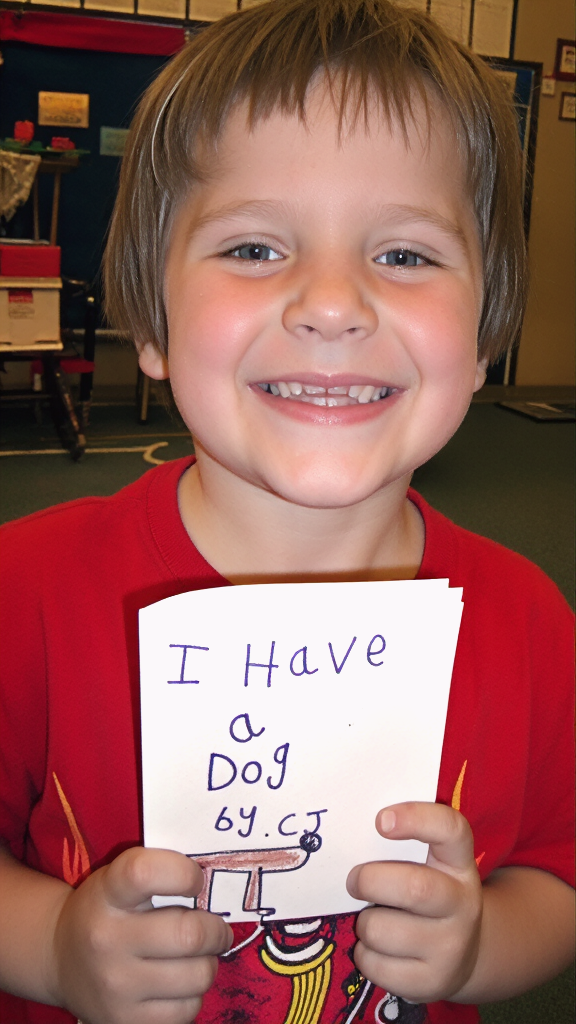 A young boy shows off a little book he wrote and made