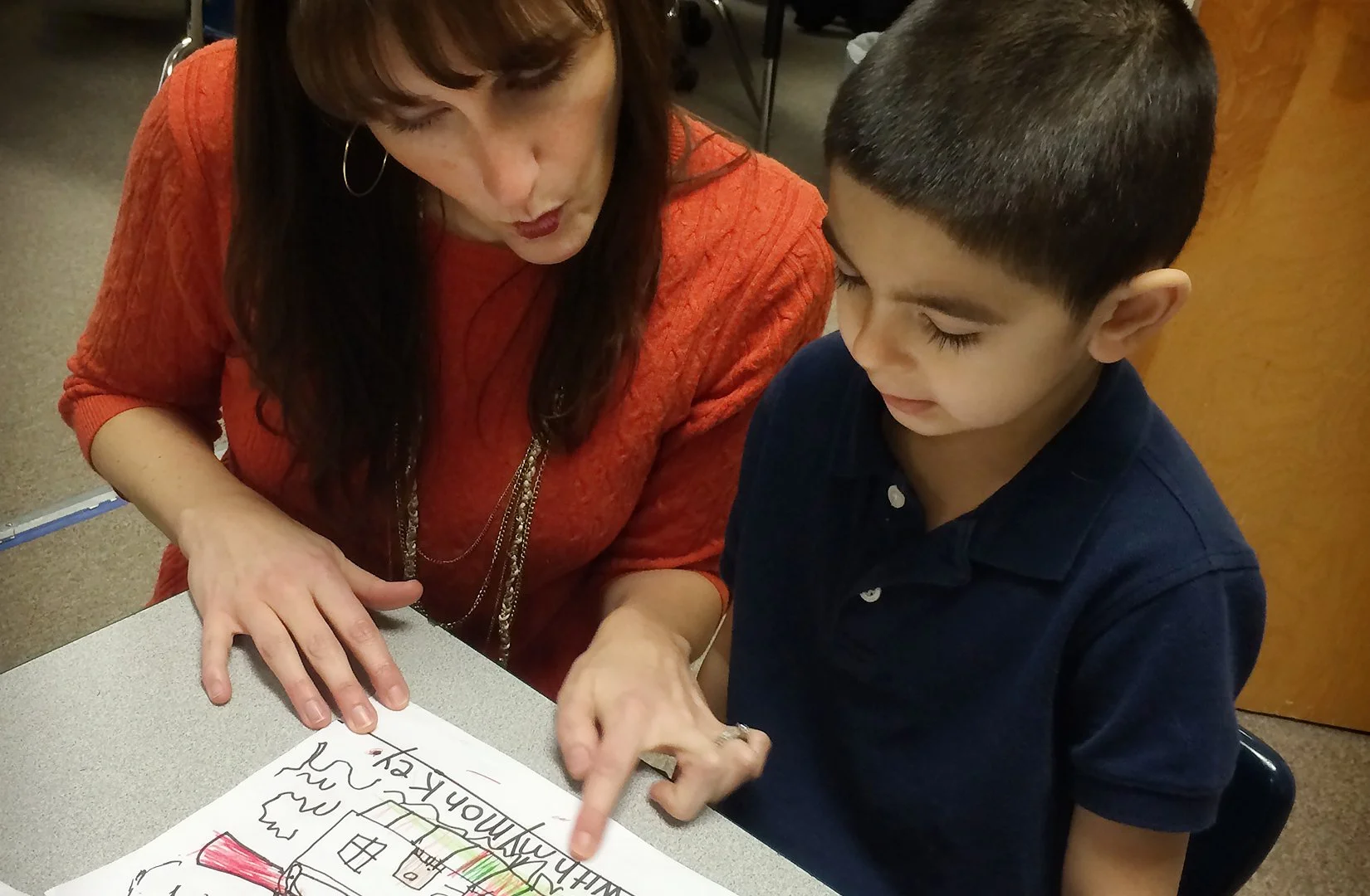 Kindgarten teacher helping young student