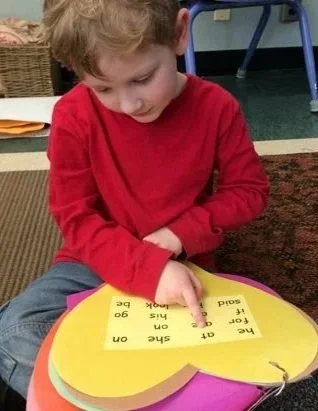 A young boy points to the heart words he knows how to read