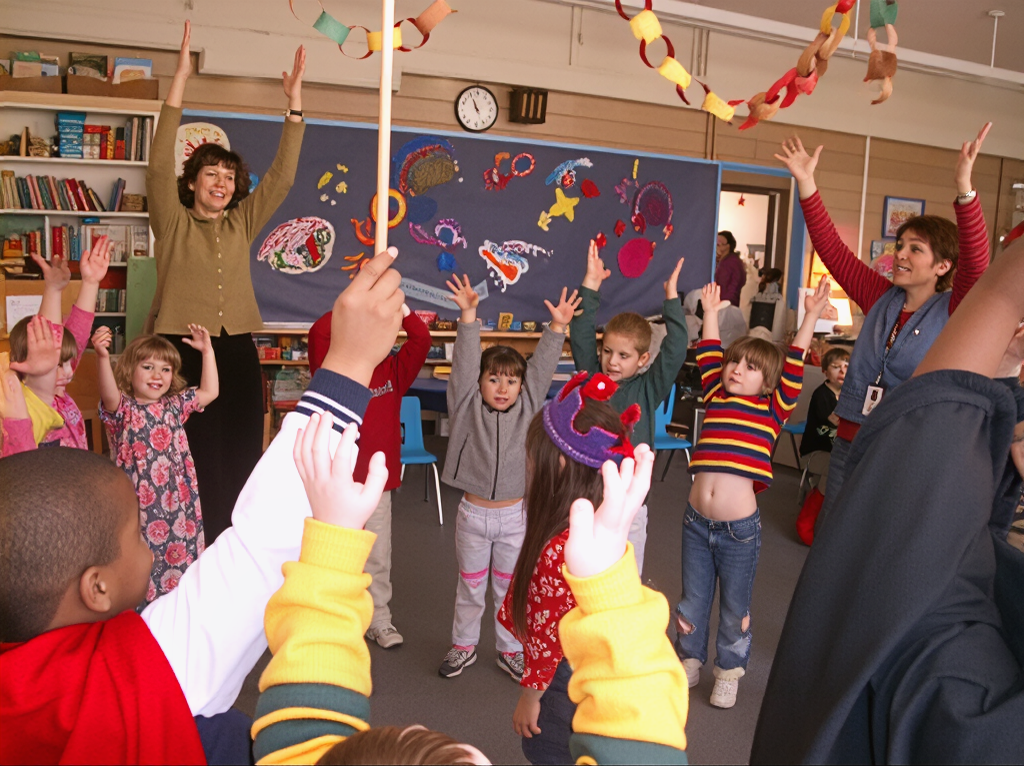 Children and teachers play and move in a classroom