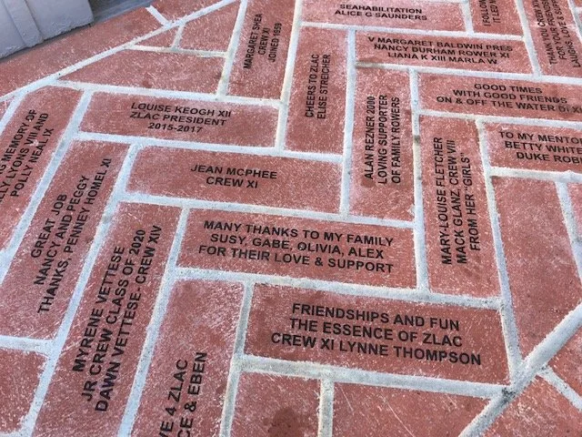 Photo of a brick wall with engraved tributes and messages for loved ones and community members.
