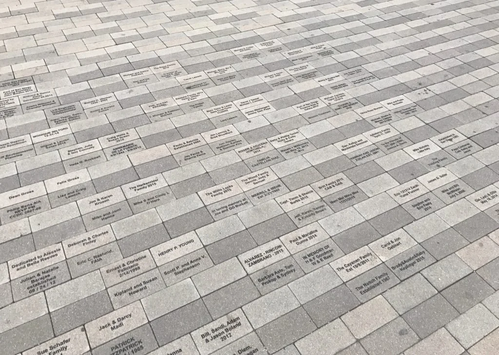 A floor with engraved memorial plaques dedicated to various individuals and families.