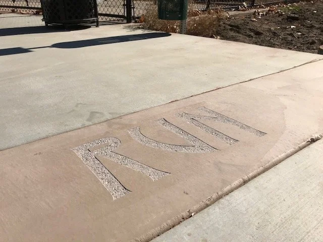 Close-up of the word 'RUN' engraved in a concrete sidewalk.