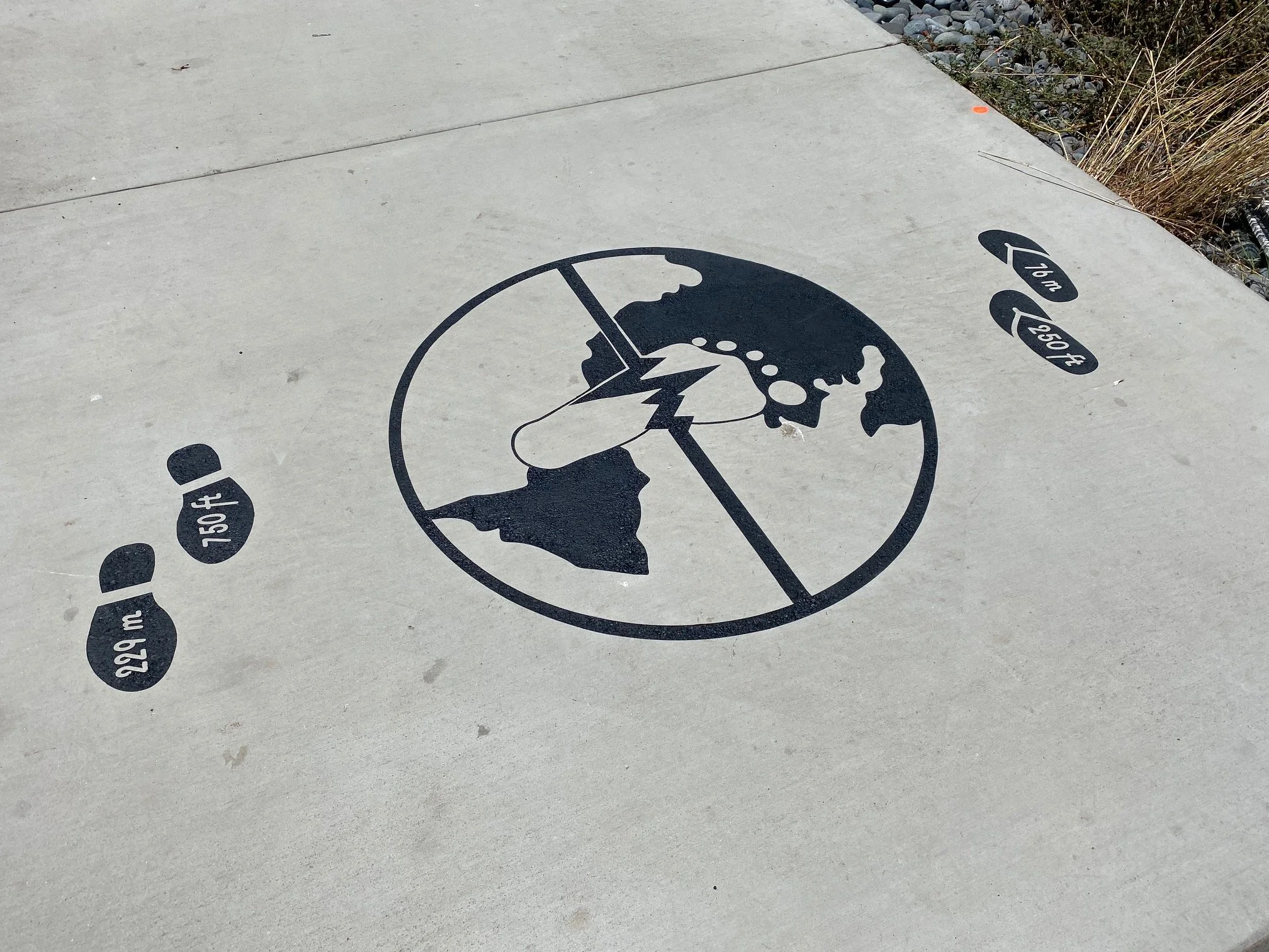 Concrete sidewalk with black markings indicating an earth globe and tire tracks with heights labeled in inches, including 1.5 inches, 2 inches, 2.5 inches, and 3 inches.