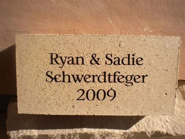 A stone plaque engraved with the names Ryan & Sadie Schwerdtfeger and the year 2009.