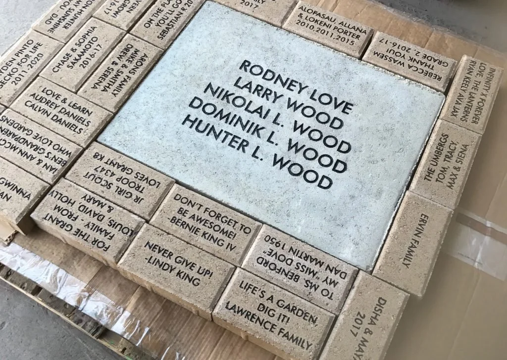 Memorial bricks with names and messages, surrounding a large brick with names of the Rowney family.