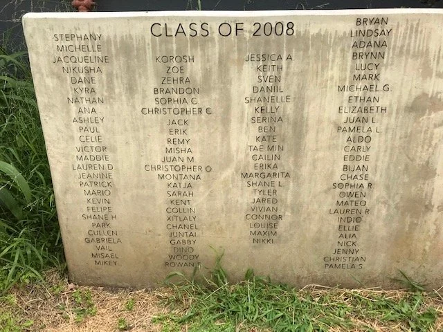 Photo of a cement memorial plaque with names of class of 2008 graduates, inscribed with headings and multiple student names arranged in columns.