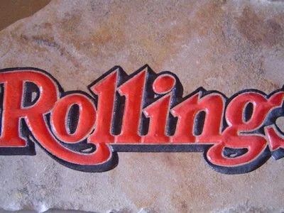 Close-up of a stone wall with part of a red and black Rolling Stones sign.