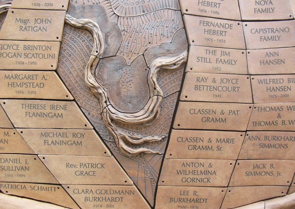 A memorial plaque with names and dates engraved, featuring a map outline of a geographic area in the center.