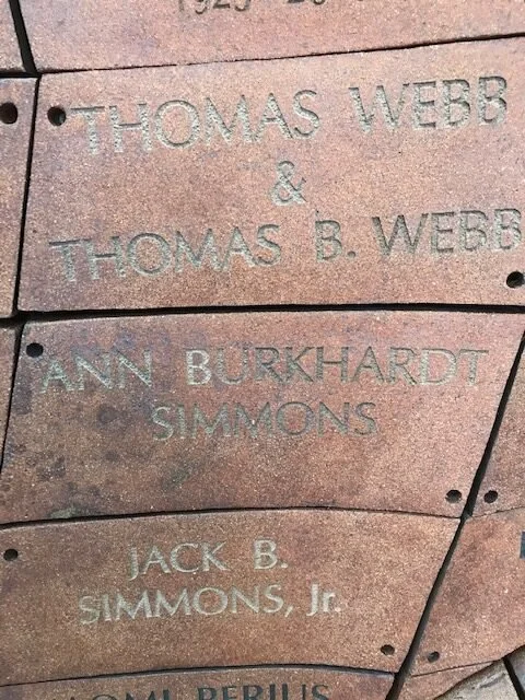 Close-up of engraved names on a brick memorial or wall, including Thomas Webb, Thomas B. Webb, Ann Burkhardt Simmons, and Jack B. Simmons Jr.