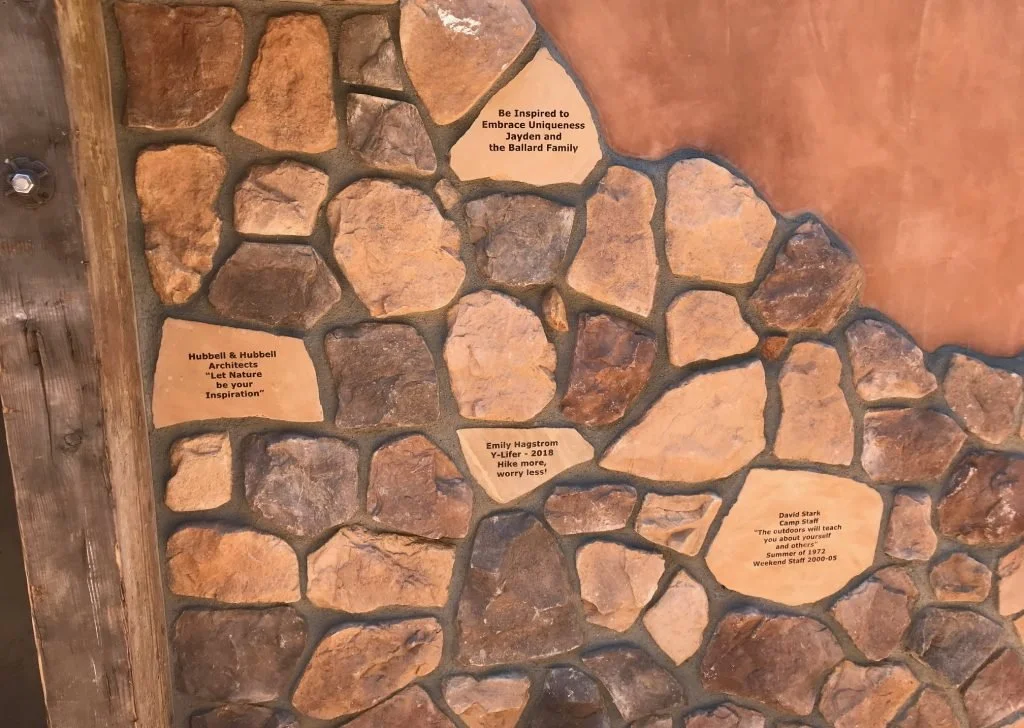 A stone wall with four plaques containing inspirational quotes.