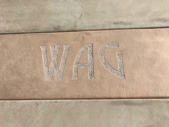 Close-up of a cardboard surface with the letters 'WAG' embossed or engraved into it.