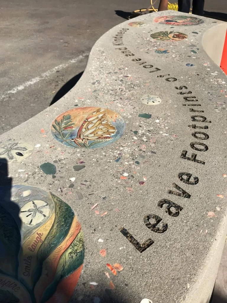 A memorial bench with colorful painted tiles and the inscription 'Loving to Remember' engraved in the concrete