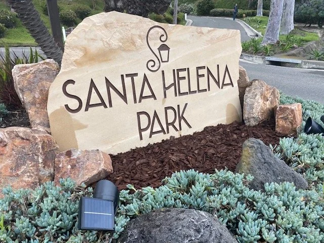 Stone sign that reads 'Santa Helena Park' with surrounding succulent plants and rocks.