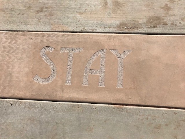 Close-up of a concrete slab with the word 'STAY' engraved into it.