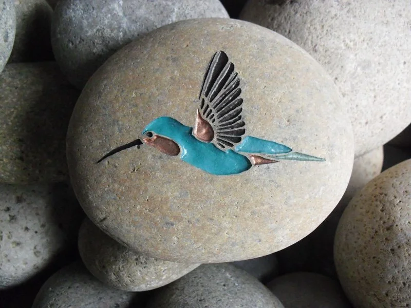 Decorative stone with a painted hummingbird design.