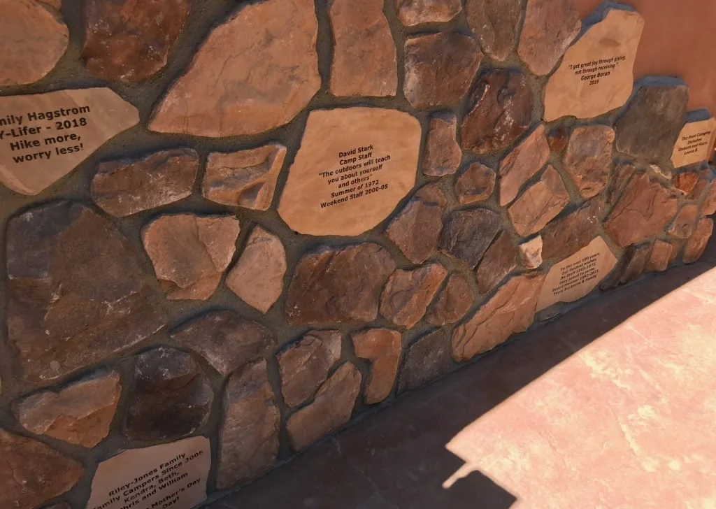 Close-up of a stone wall with engraved plaques displaying quotes or memories.