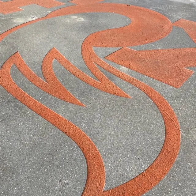 Close-up of a painted red and gray swirl design on a concrete sidewalk.