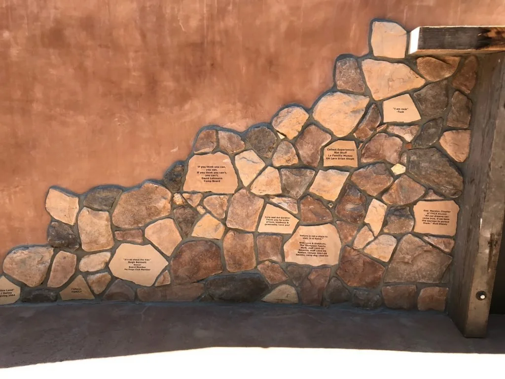 Stone wall with embedded plaques and quotes about nature and exploration.