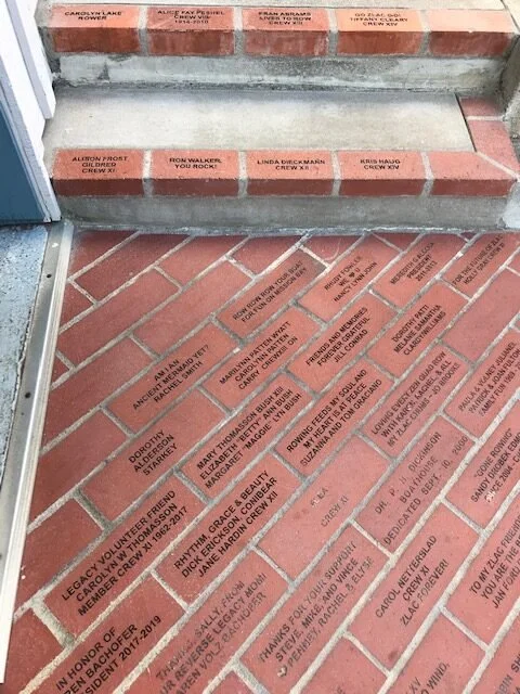 Brick sidewalk with commemorative engraved bricks in honor of various individuals, arranged in rows.