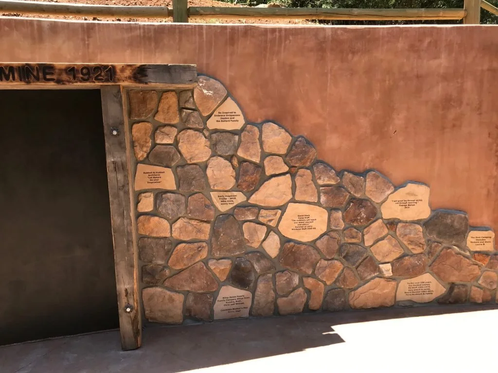 A stone and wood wall commemorating the mine's history, with plaques detailing historical facts and achievements.