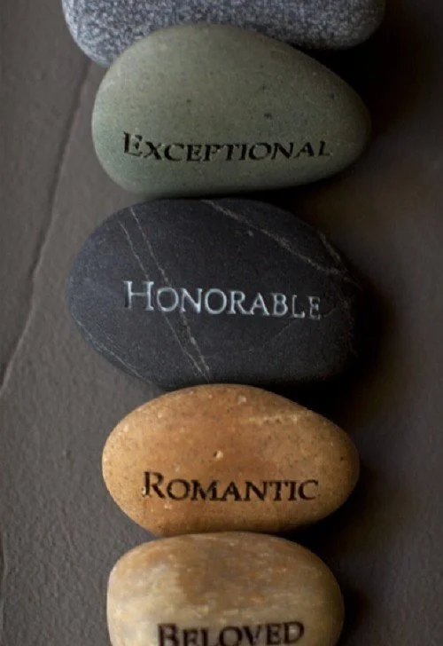 Four stones arranged vertically with engraved words: 'Exceptional', 'Honorable', 'Romantic', and 'Beloved'.