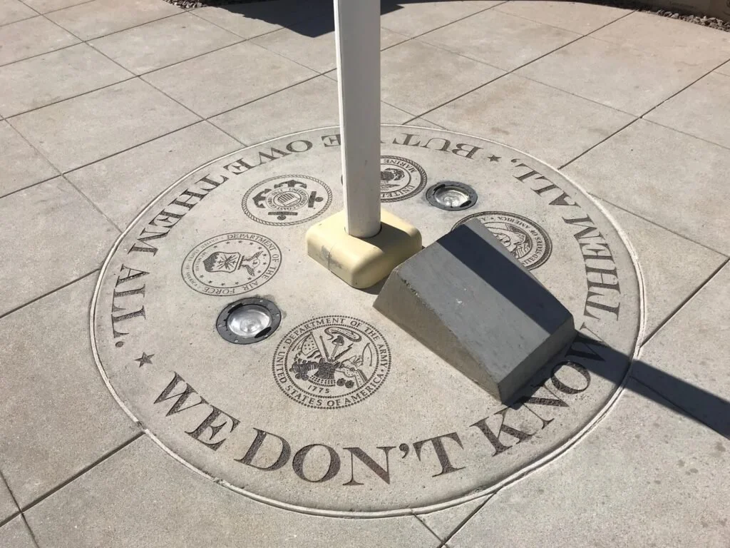 U.S.-Mexico border marker with the text "WE DON'T KILL" and official seals around the border line.