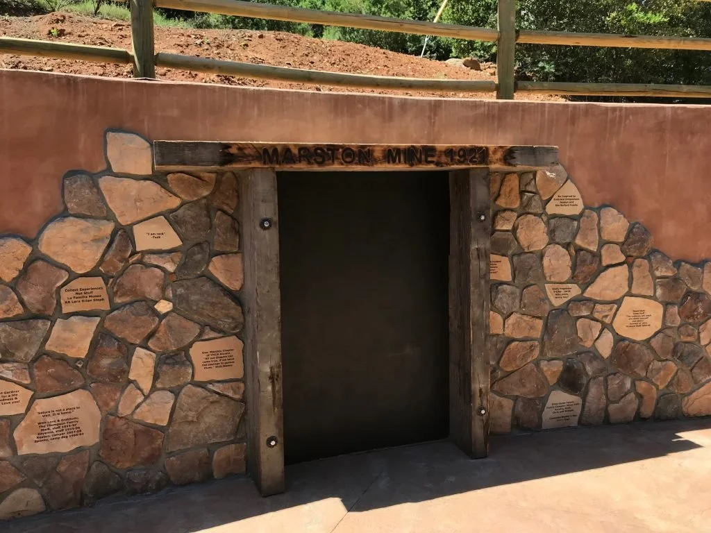 Entrance to the Marston Mine, established in 1921, set into a stone and wood wall with plaques and a wooden sign above.