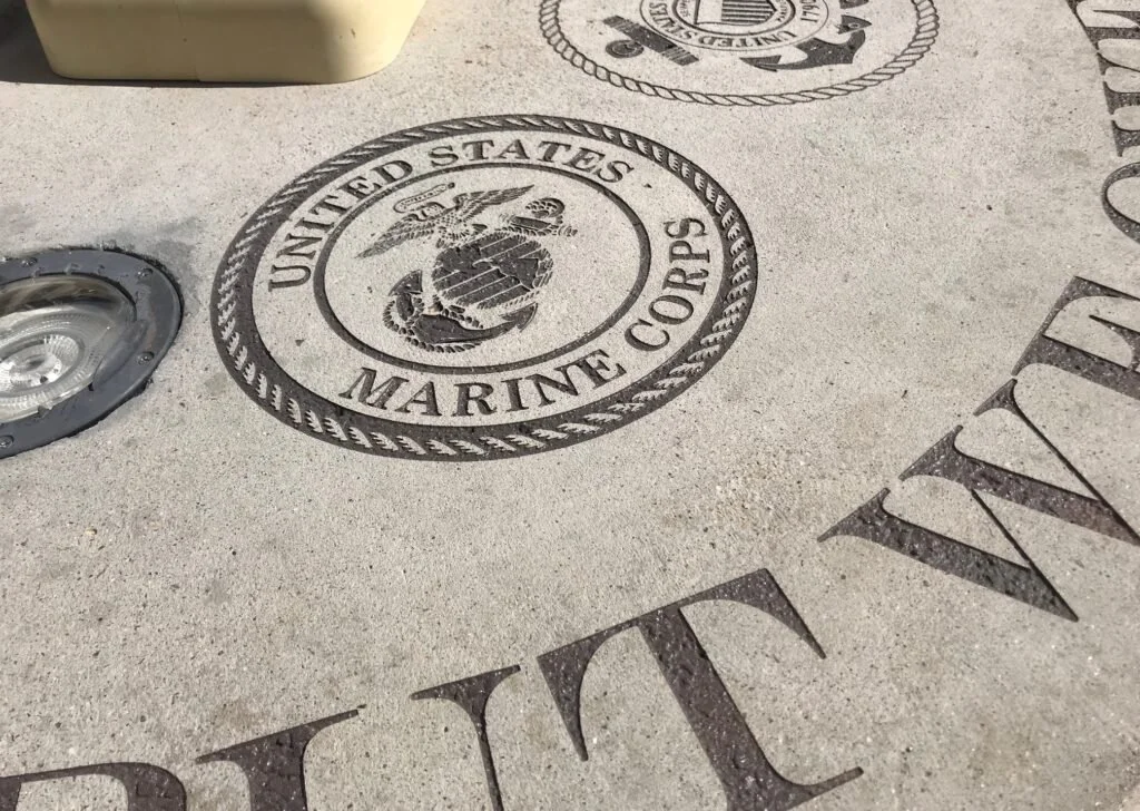 Marine Corps emblem embedded in concrete with a Marine insignia and U.S. Marine Corps text.