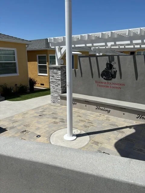 Memorial tribute at Warrior Foundation Freedom Station with a wall bearing a silhouette of a soldier and the words 'Warrior Foundation Freedom Station' and 'Healing'.
