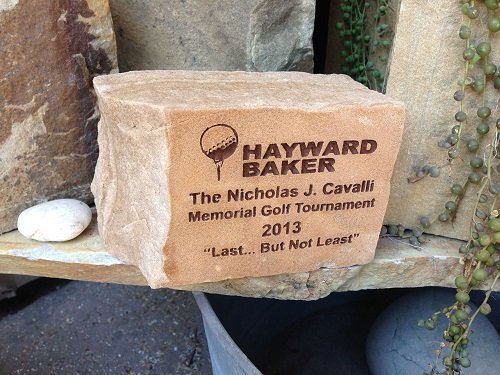 A stone engraved with the Hayward Baker logo and text for the Nicholas J. Cavalli Memorial Golf Tournament 2013.