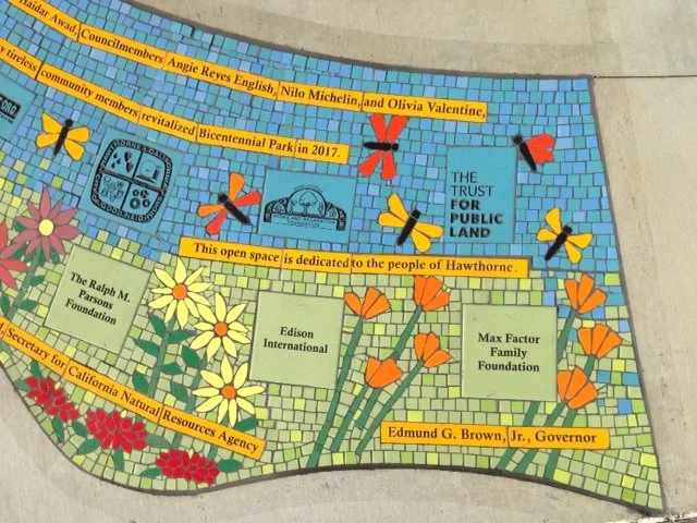 Colorful mosaic with cartoon flowers and butterflies, plaques, and text dedicating open space to Hawthorne community, with names of local foundations and a quote about public land.