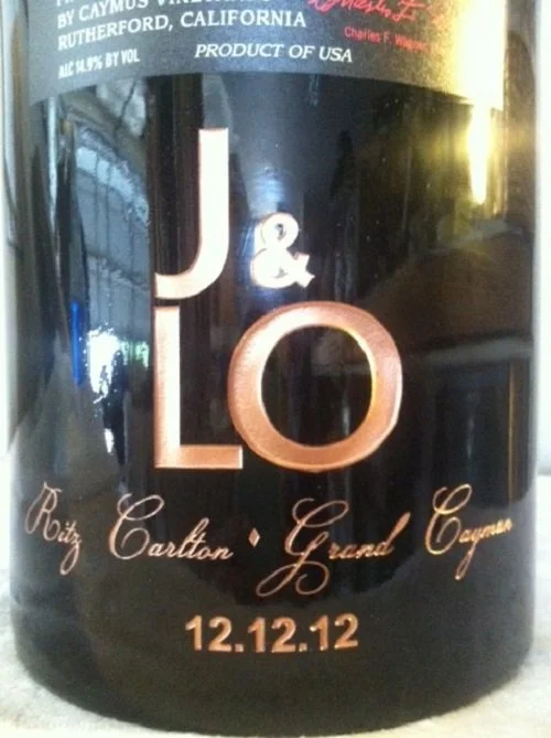 A black bottle label with gold and white text, displaying the name J & L, and below it, the names Bob and Carlton with a dot between them and Grand Canyon. The date 12.12.12 is at the bottom of the label.