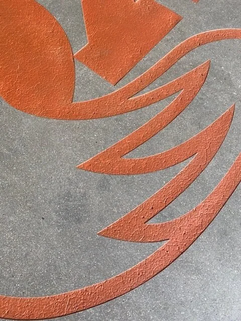 Close-up of an orange and gray abstract design or logo on a textured surface.