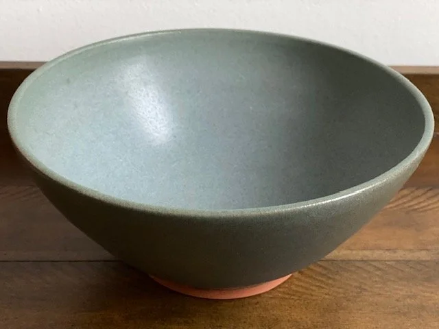 Empty blue/grey ceramic bowl placed on a wooden surface. Sonia Lesage Ceramics