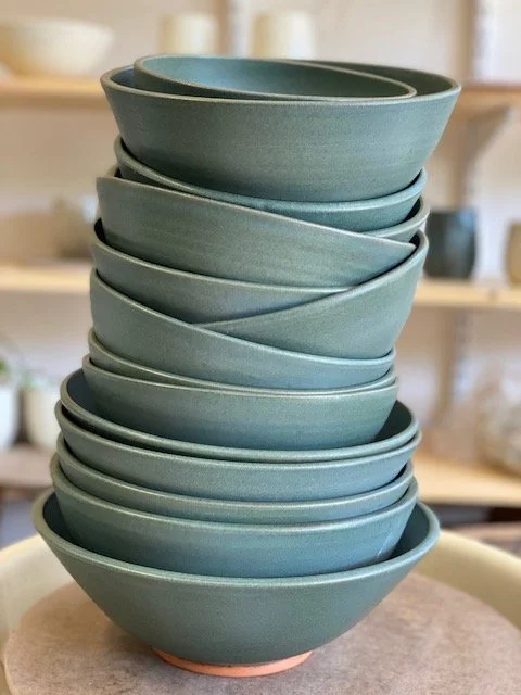 Stack of blue ceramic bowls on a pottery wheel. Sonia Lesage Ceramics
