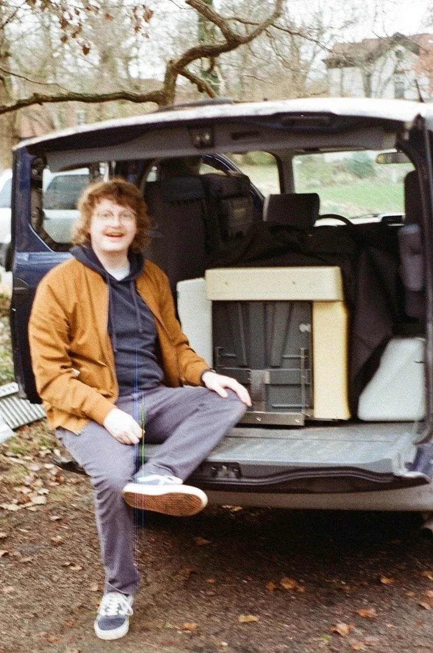 Get Home Safe's owner and operate smiles in the backseat of his 2003 Honda Element, containing the Risograph GR3750 that started it all. he smiles with his mouth open, mid sentence addressing the photographer, amy applegate.