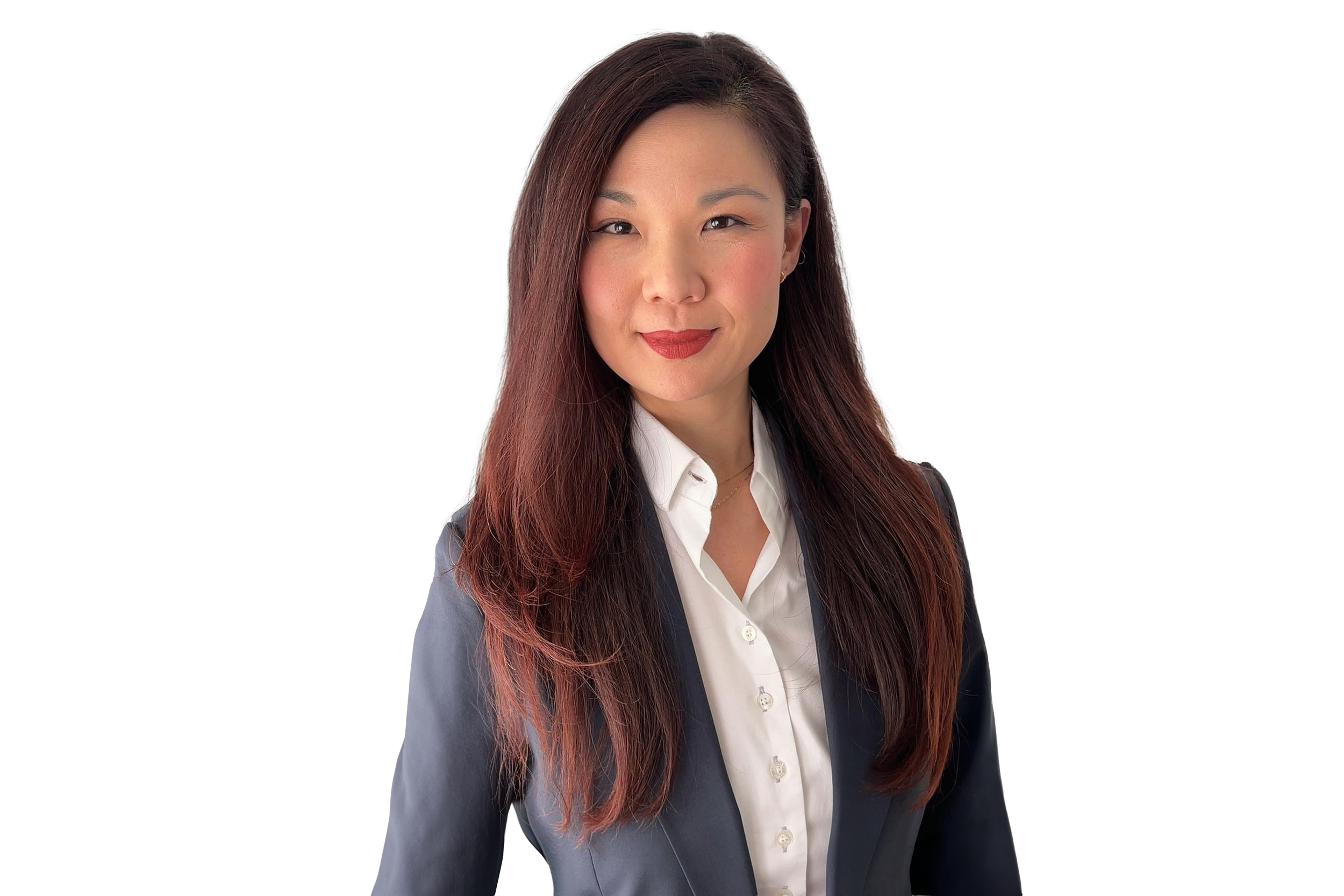 A woman with long, reddish-brown hair, wearing a white collared shirt and a dark blazer, smiling softly at the camera.