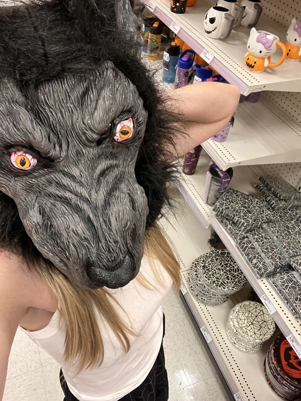 Whitney Bishop wearing a werewolf mask in a store Halloween aisle.