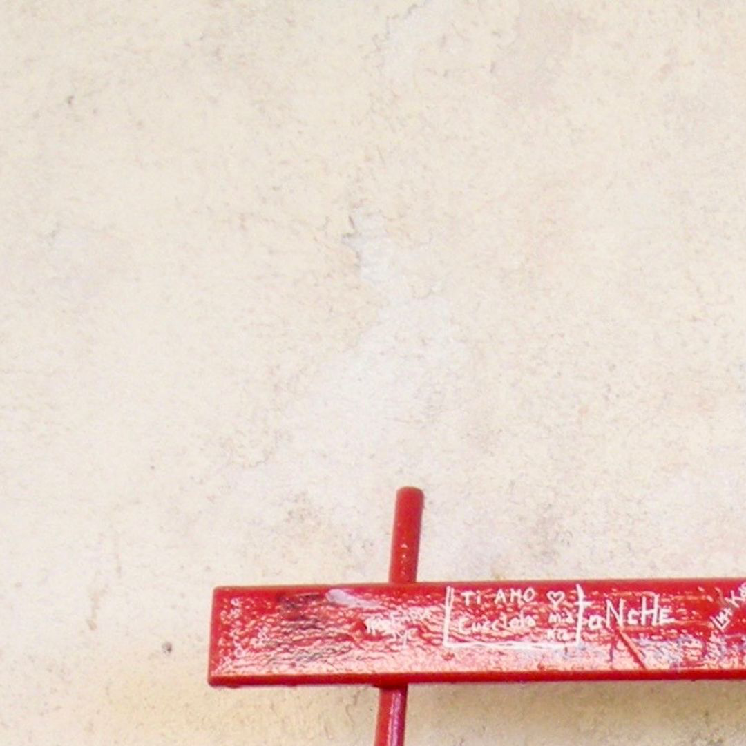 Red graffiti-covered bench against a pale wall